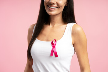 Smiling woman wearing pink ribbon for breast cancer awareness month
