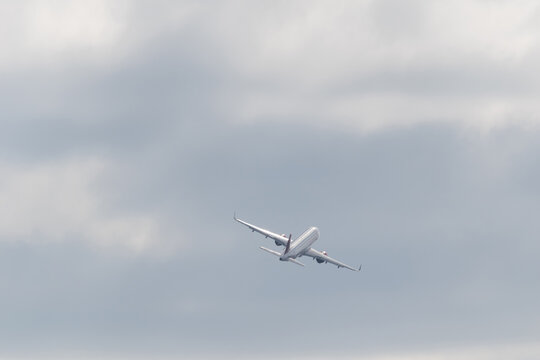 commercial airliner taking off with clouds in the background, passenger plane silhouette in distance