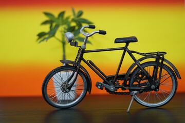 A miniature vintage bicycle in a studio setup, set against a warm gradient backdrop