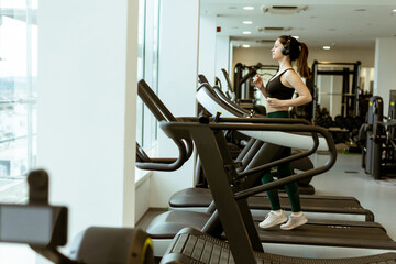 Woman jogging on treadmill in modern gym during early morning workout session