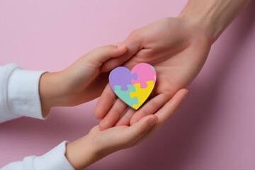 Child and adult hands holding multicolored puzzle heart symbolizing autism awareness