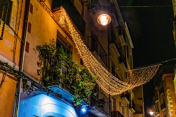 Medieval street in Girona, Spain during Christmas season with festive decorations. Contrast between...