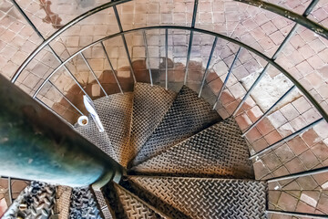 View down a spiral metal staircase in Girona, Spain, with steel treads and minimalist railings. A...