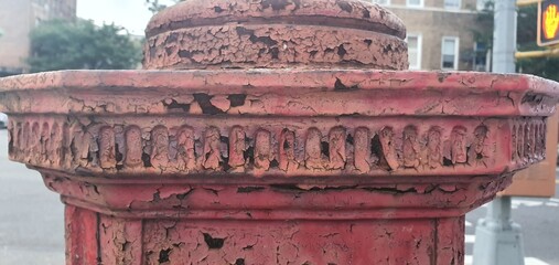 Close-up of a weathered architectural column with decorative leaf and ribbon patterns in white...