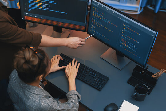 Top view of IT developers discussing with point to intelligent website development coder system running data online two screens information technology at neon light room at modern office. Infobahn.