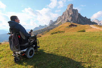 Man with disability using wheelchair explores the stunning landscape of Giau Pass at Dolomites in...