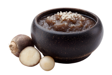 Bowl of arrowroot porridge topped with small white seeds next to arrowroot bulbs