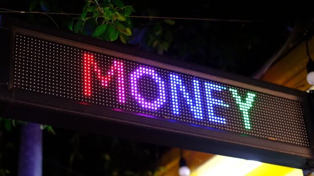 A sign that says money in neon lights. The sign is lit up and is in a dark setting