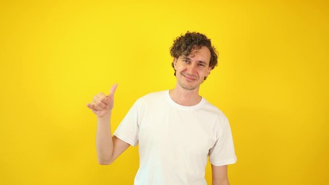 Confident man in white t-shirt showing shaka hand gesture, isolated on yellow studio background &mdash; a vibrant visual perfect for travel campaigns, surf culture branding, and World Hello Day promotions