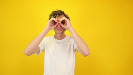 Surprised man in white t-shirt mimicking binoculars with hands, then lowering them and exclaiming WOW dynamic visual ideal for sales campaigns, discount promotions, black friday, cyber monday content