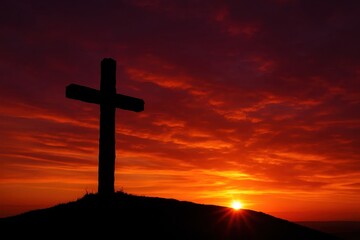 Dramatic silhouette of a Christian cross atop a hill, bathed in the breathtaking, fiery glow of a vibrant red and orange sunset, symbolizing hope and sacrifice.