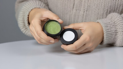 white sticker on green cream can in the hand of a person in a bathrobe