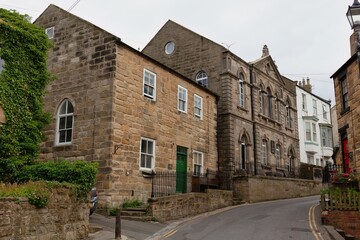 Stone buildings line a narrow, winding road in this landscape image  in Staithes - North Yorkshire - United Kingdom