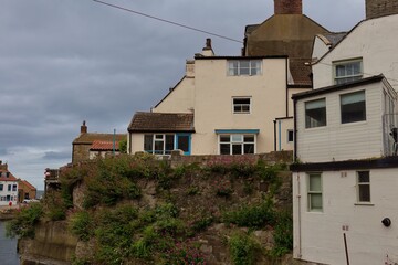 Whitewashed buildings appear on a bank overlooking water  in Staithes - North Yorkshire - United Kingdom