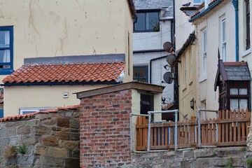 Exterior shot of houses. There is orange brick, red tiling, stone, and wood fencing; the houses...