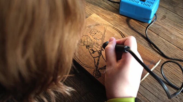 Burn out the picture. Woodburning or pyrography. An artist drawing on a wooden plank with pyrograph. Wood burning ASMR creative hobby. Art class workshop. Creative activity. High quality 4k footage.