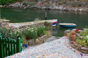 A quaint view of a body of water with two small boats docked near a mosaic path  in Staithes - North Yorkshire - United Kingdom