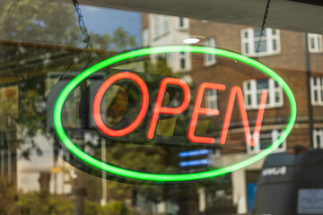 Bright neon OPEN sign in shop window with green oval border