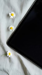 Stock photo of tablet mockup with daisies on white fabric background for advertising