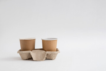 Two paper coffee cups in a cardboard sleeve on a white background
