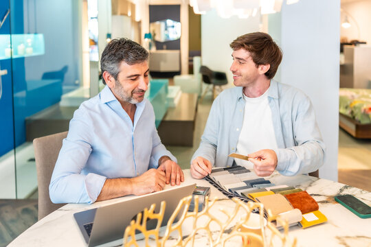 Interior designer showing fabric swatches to customer in furniture store - Powered by Adobe