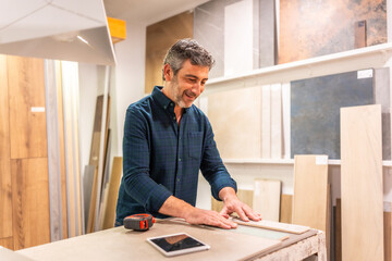 Architect choosing tiles and wood samples in showroom with tablet and tape measure
