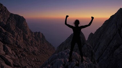 Silhouette of triumphant female climber standing atop mountain peak during breathtaking sunset