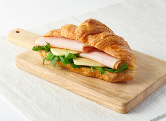 Smoked Turkey and Mozzarella Croissant Sandwich with Arugula on Wooden Board side view of deli menus