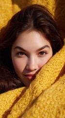 A captivating close-up portrait of a young woman, her warm gaze inviting viewers to connect, as she is enveloped in a cozy yellow embrace, suggesting comfort and optimism.