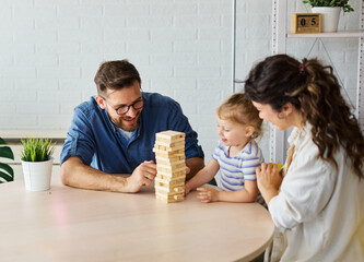 Portrait of a happy amily at home, having fun playing wooden brick challenge game, playing board...