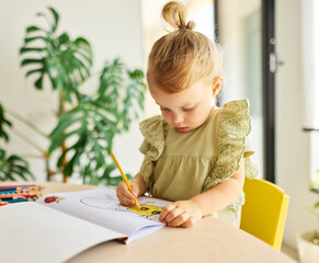 Portrait of a little girl coloring a book in classroom or at home. Education and development...