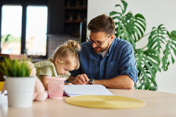 Portrait of a little girl and father or teacher coloring a book in classroom or at home. Education and development concepts