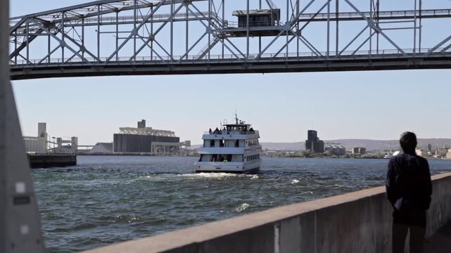 Man watches ferry passenger boat go under lift bridge, Duluth, Minnesota, United States
