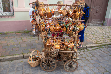 Wooden cart displaying traditional handcrafted mugs and kitchen utensils at a street market