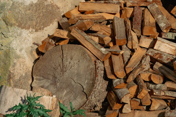 Stack of Split Firewood and Tree Stump by Stone Wall – Rustic Countryside Scene with Natural Warm...