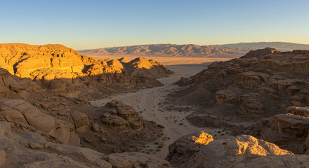 Panoramic Desert Landscape with Rugged Rock Formations and Sandy Valleys in Golden Light