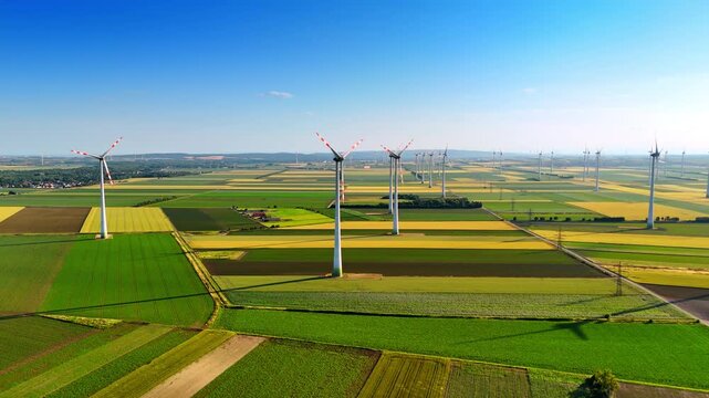 Colorful patched field with wind farms. Vast plantations with numerous wind mills working on. Aerial view.