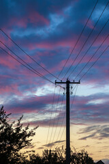 Wires and poles, Electric power transmission against a beautiful sky with clouds at sunset in the countryside