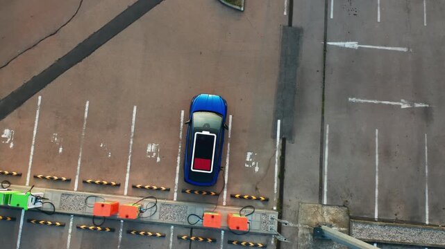 Electric car with power charging indicator on roof connected to public charging station at parking lot. Modern vehicle receives electricity in city