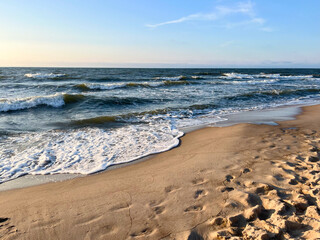 Golden sand beach with sea waves at sunset in Mielno, Baltic Sea coast, Poland