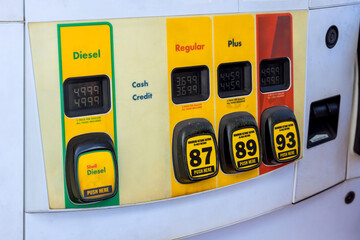Fuel dispensers show various fuel types, prices while drivers refuel their vehicles at busy urban...