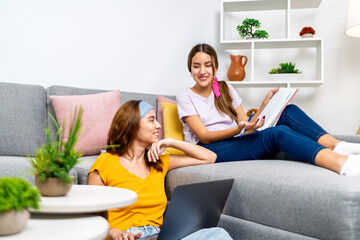 Two female students collaborating on homework in living room