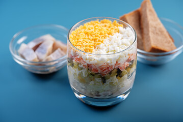 Herring layered salad with potatoes and eggs in a glass