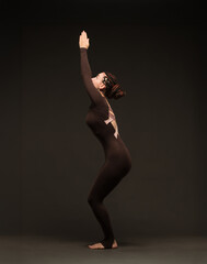 professional yoga girl doing exercises on dark background.young lady in brown sportswear on dark...