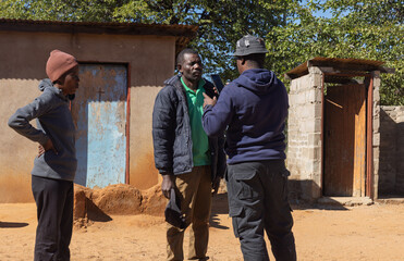 Africa village, charity social worker biometrics in the phone with entrepreneur villagers, standing...