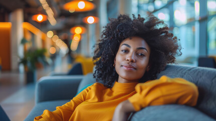 Portrait of a confident woman in a modern office lounge, exuding relaxation and approachable professionalism.
