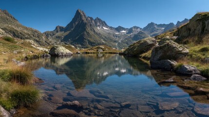 Beautiful reflective surface of calm lake mirroring mountain peaks under blue sky
