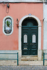 Tall, ornate, green door with windows, arch, pink wall, and number 100 street number decal and...