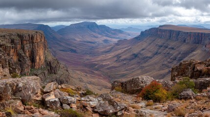 Obraz premium Rocky plateau overlooking vast mountain ranges under heavy overcast sky