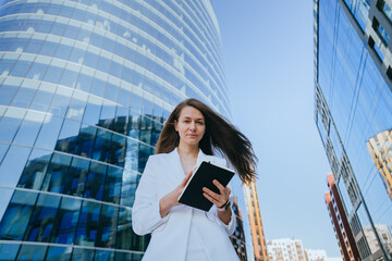 A joyful woman with outstretched arms radiates excitement in front of a sleek glass building, embracing a new day.